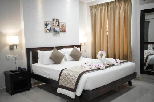 a bedroom with a bed with white sheets and pillows at Hotel Vista Suites, Bangalore in Bangalore