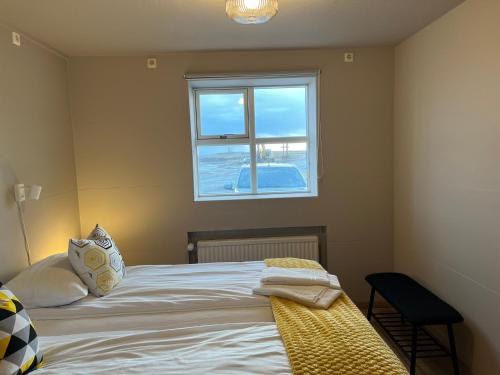 a bedroom with a bed with a window at Guesthouse Hvammur by the Harbour in Höfn