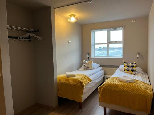 a small room with two beds and a window at Guesthouse Hvammur by the Harbour in Höfn