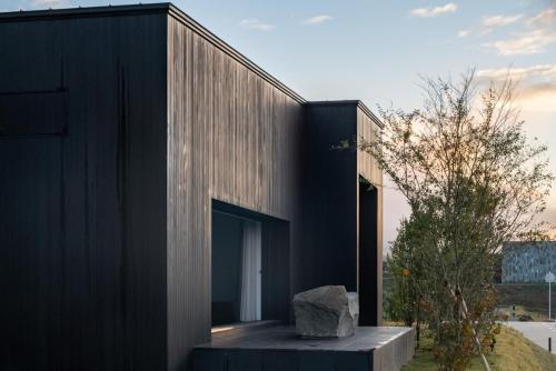 a black house with a rock in front of it at 歓宿縁 eshikoto in Eiheiji
