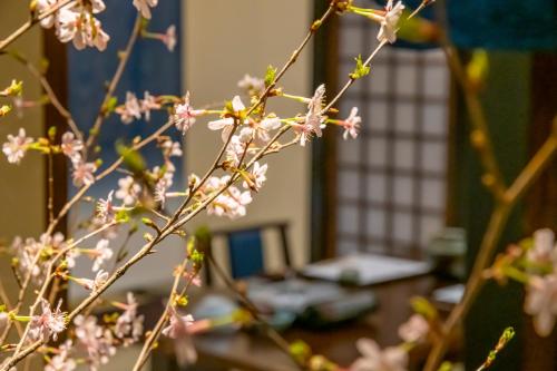 a branch with pink flowers in front of a table at 岩井温泉　岩井屋 in Iwamicho