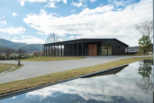 a large black building with a reflection in the water at 歓宿縁 eshikoto in Eiheiji