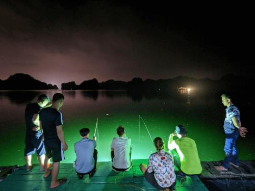 a group of people sitting on a dock at night at Tung Quang Hotel in Cat Ba