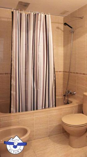 a bathroom with a shower curtain and a toilet at Altur 5 Canfranc Estación in Canfranc-Estación