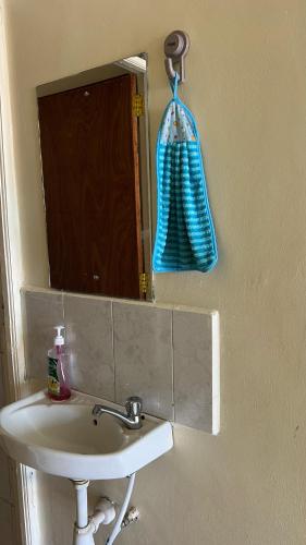 a bathroom sink with a mirror and a blue hand towel at Shalom Apartments Utawala near JKIA Airport in Nairobi
