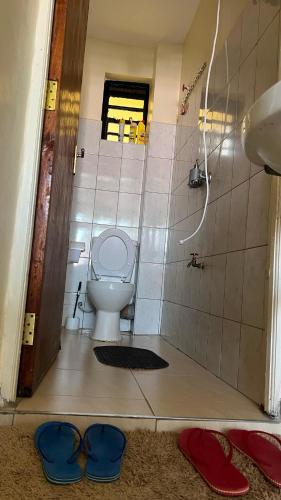a bathroom with a toilet and a sink and some slippers at Shalom Apartments Utawala near JKIA Airport in Nairobi