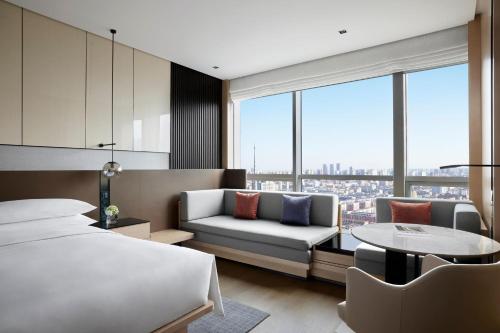 a bedroom with a bed and a couch and a table at Shenyang Marriott Hotel in Shenyang