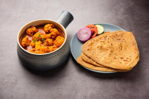a bowl of food next to a plate with a bowl of food at FabExpress Elysian Grand - 3 kms from Chaudhary Charan Singh International Airport Lucknow in Lucknow