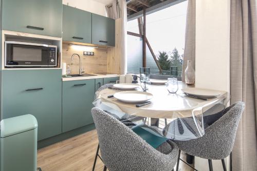 une cuisine avec une table et des chaises et une cuisine avec un comptoir dans l'établissement Le Manchot - Au pied des remontées mécaniques, à Chamrousse