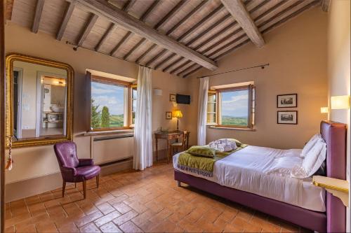 Un dormitorio con una cama y una silla y ventanas. en Villa Demetra, en Sarteano