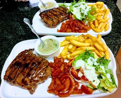 two plates of food with meat and french fries at A Cherry Lane Self Catering and B&B in Bloemfontein