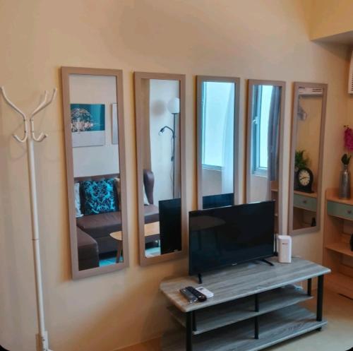 a living room with a tv and mirrors on the wall at Sunset Suite in Iloilo City