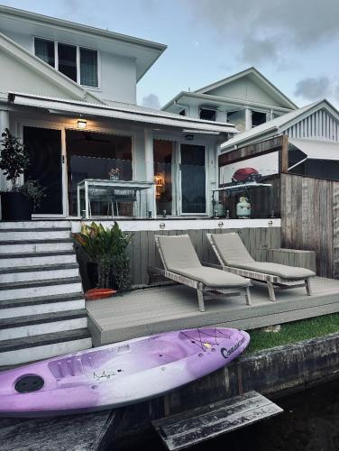 a purple surfboard sitting next to two chairs and a house at Noosa Waters Retreat in Noosaville