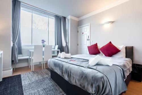a bedroom with a large bed with red pillows at 1 Riverside Apartments in Norwich