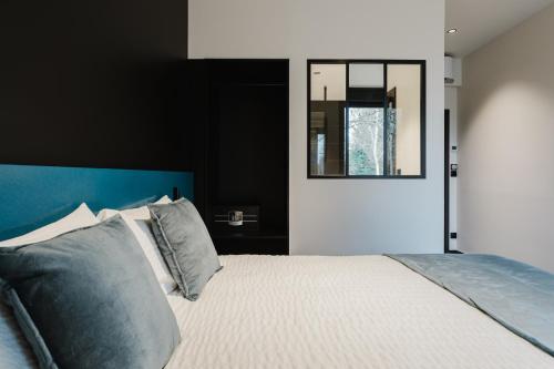 a bedroom with a bed with a blue headboard and a mirror at Les Lodges de Socrate in Le Vaudreuil