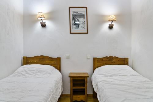- 2 lits dans une chambre avec 2 lampes sur le mur dans l'établissement Résidence Les Hauts De Preclaux - Charmant studio tout proche des commerces MAE-8041, aux Orres