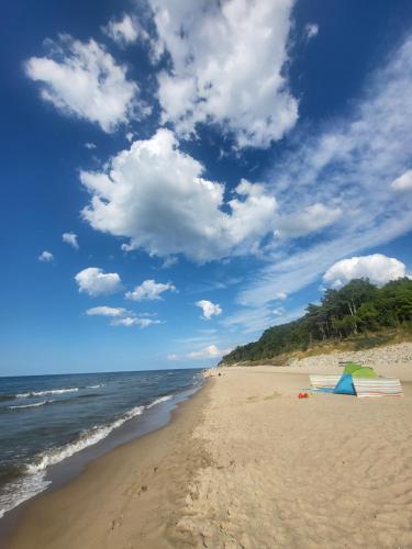 a sandy beach with a blue sky and the ocean at Sun Paradise in Rewal