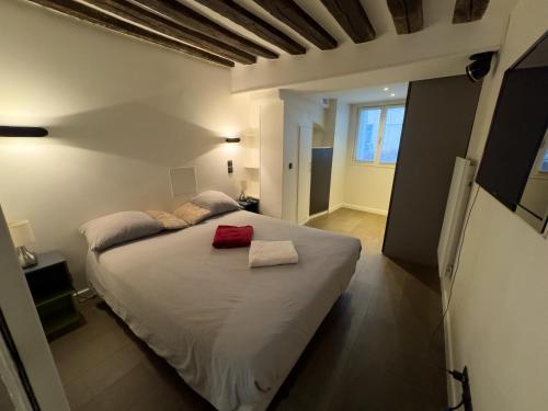 a bedroom with a large white bed with a red pillow at Appartement design au cœur du Marais in Paris