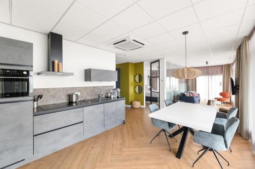 a kitchen and dining room with a white table and chairs at Suites aan Zee in Vlissingen