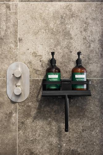 two bottles of soap on a shelf in a bathroom at Suites aan Zee in Vlissingen