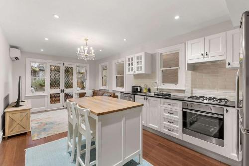 a kitchen with white cabinets and a wooden counter top at Perfect Vacation Home w Large Outdoor Space in Sydney