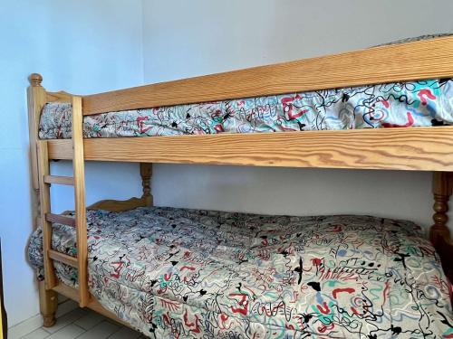 - un lit superposé en bois avec un couvre-lit floral dans l'établissement Studio cabine 4 couchages ARGELES SUR MER AR240-112, à Argelès-sur-Mer