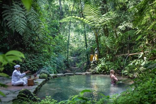 a man and a child in a pool in a jungle at Pramana Giri Kusuma in Payangan