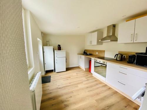 une cuisine avec des appareils électroménagers blancs et du parquet dans l'établissement Agréable maison en centre ville de St Mère Église, à Sainte-Mère-Église