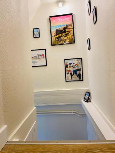 un escalier avec des photos sur la paroi dans l'établissement Agréable maison en centre ville de St Mère Église, à Sainte-Mère-Église