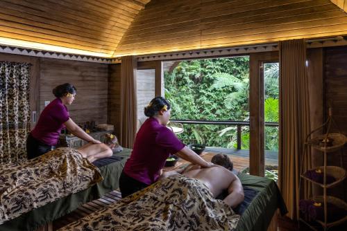 a group of people sitting on beds in a room at Pramana Giri Kusuma in Payangan