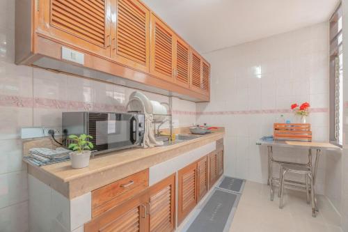 a kitchen with wooden cabinets and a sink at Manim House - บ้านพักในนิมมานพร้อมไวไฟ in Chiang Mai