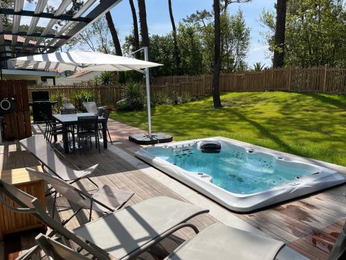 - un bain à remous sur une terrasse avec des chaises et un parasol dans l'établissement Golfaozean, à Anglet