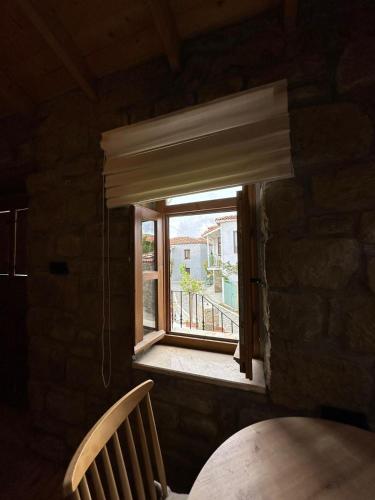 a window in a brick wall with a table and a chair at Paleos İmroz in Gökçeada