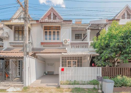 a white house with a fence in front of it at Manim House - บ้านพักในนิมมานพร้อมไวไฟ in Chiang Mai