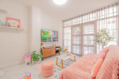 a living room with a pink bed and a tv at Manim House - บ้านพักในนิมมานพร้อมไวไฟ in Chiang Mai