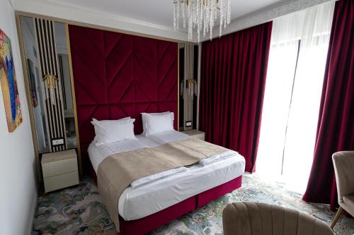 a bedroom with a large bed with a red headboard at CHITULESCU Hotel in Târgovişte