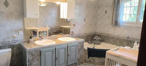 une salle de bain avec deux lavabos et une baignoire dans l'établissement Magnifique maison Piscine et Spa 5mins des plages, à Elne