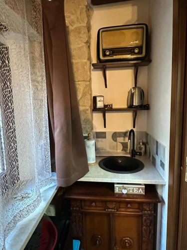 a kitchen with a sink and a tv on a counter at La Casa delle Rondini in Baunei