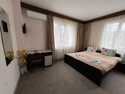 a bedroom with a bed and a desk and window at Park Hotel Ivailo in Veliko Tŭrnovo