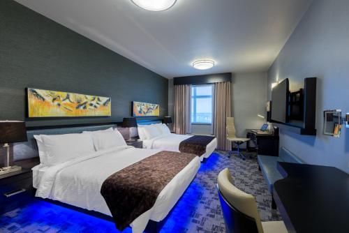 a hotel room with two beds and a desk at Applause Hotel Calgary Airport by CLIQUE in Calgary
