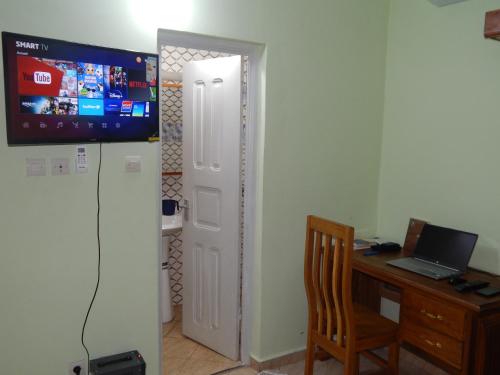 ブラザヴィルにあるNzing Apartmentsのデスク、コンピュータ、テレビが備わる客室です。