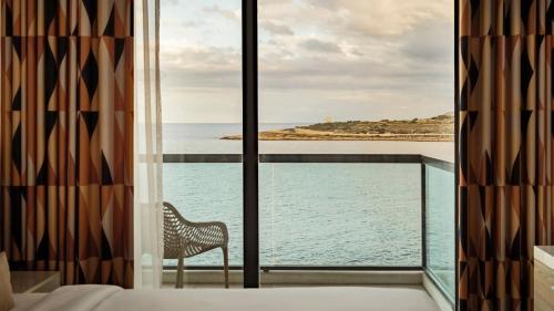 a bedroom with a view of the ocean from a window at AX ODYCY Hotel in St Paul's Bay
