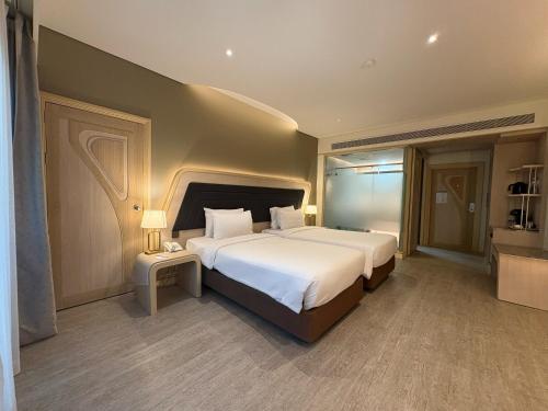 una camera da letto con un grande letto bianco e un tavolo di Amora Beach Resort Phuket a Bang Tao Beach