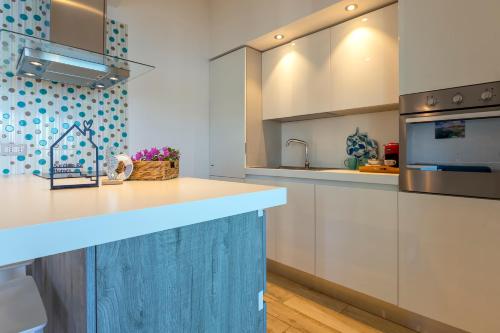 una cucina con armadi bianchi e isola blu di SARDINIA RE - Porto Conte Bay Terrace a Porto Conte