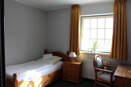 a bedroom with a bed and a desk and a window at Hotel Am Steendamm in Oyten