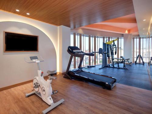 a gym with exercise equipment and a flat screen tv at Mercure Garut City Center in Garut