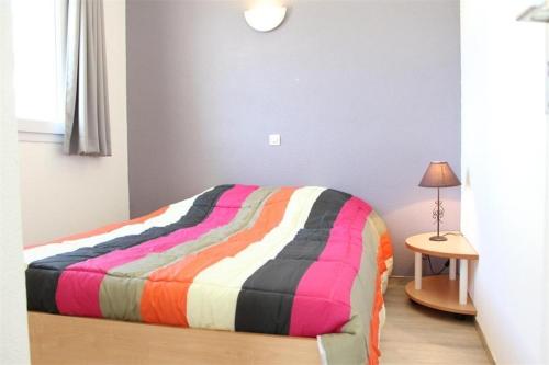 - un lit avec une couverture rayée colorée dans l'établissement Appt 2 pièces LA ROCHELLE - LR030-E111Z, à La Rochelle