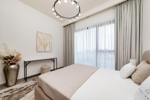 a white bedroom with a bed and a chandelier at Premium Apartments at Executive Residences in Dubai
