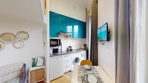 une cuisine avec des armoires bleues et une machine à laver dans l'établissement Joli studio centre-ville Nice proche de la gare, à Nice