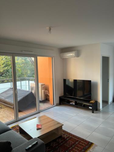a living room with a couch and a flat screen tv at Chambre cosy in Aucamville